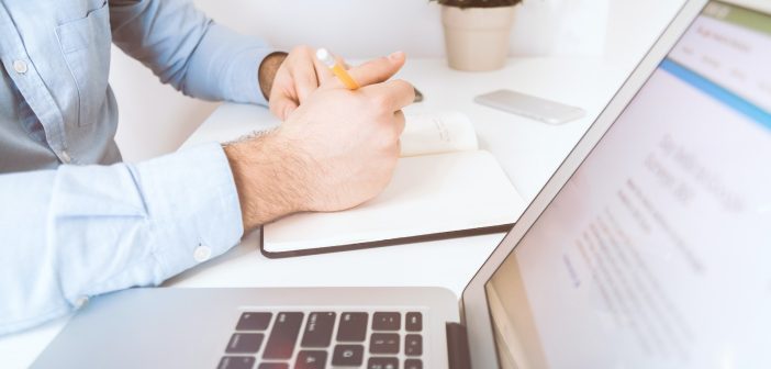 person writing on white notebook